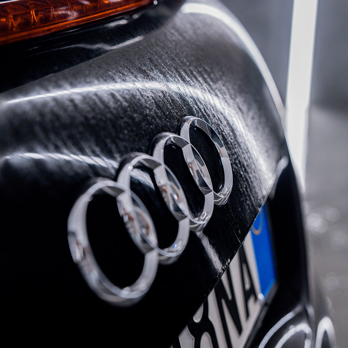 Close-up of Audi logo on a car's side panel.