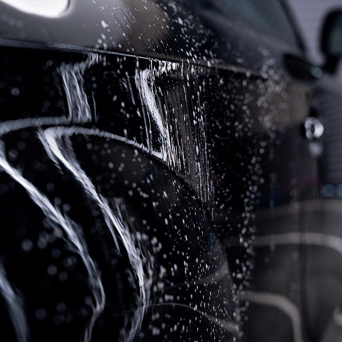 Car washing with soap suds on a black car