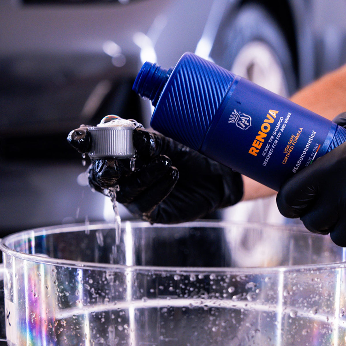 Person applying Renova car care product to a car part with a blurred car in the background