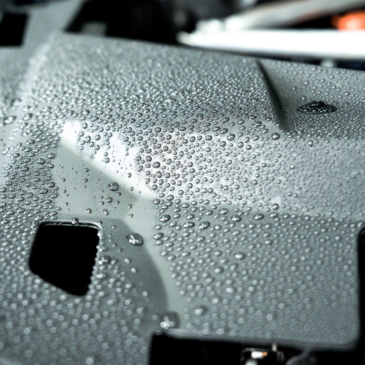 Close-up of a car's windshield with water droplets on a blurred background